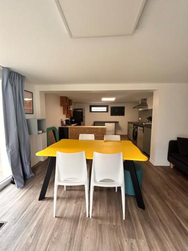 une table jaune et deux chaises blanches dans une pièce dans l'établissement Appartement rétro nature avec jardin 15 min Toulouse centre, à Saint-Geniès-Bellevue