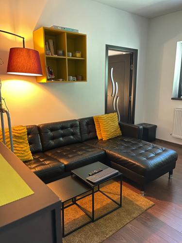 a living room with a leather couch and a table at City Garden Apartments in Bucharest