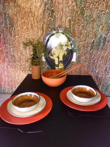 a table with two plates of coffee and a bowl at LA MAISON DES BOIS D'OCRE - Gîte Appart Design - Clim Pkg Wifi Jardin à 10mn de Dijon in Messigny-et-Vantoux