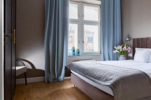a bedroom with a bed and a window with blue curtains at Browar Hevelius Apartments by Grand Apartments in Gdańsk