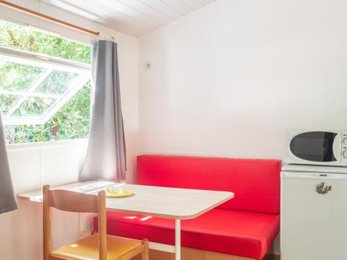 une chambre avec un canapé rouge, une table et une fenêtre dans l'établissement Camping de la Chapelette, à Saint-Martin-de-Crau