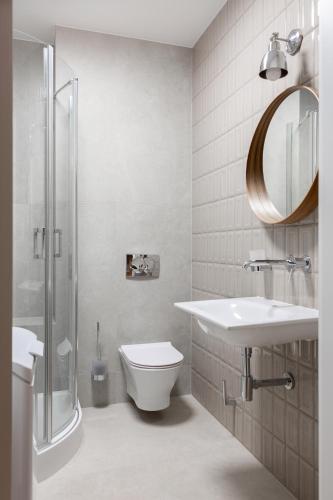a bathroom with a sink and a toilet and a mirror at Browar Hevelius Apartments by Grand Apartments in Gdańsk