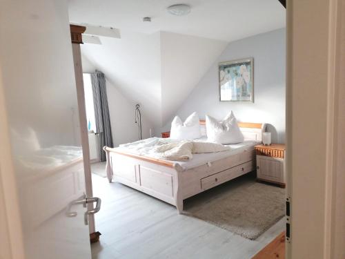 a bedroom with a bed with white sheets and pillows at Haus Tenne in Krummhörn