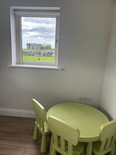 a green table and chairs in a room with a window at Idyllic, 5 Star Family Home with Panoramic Views, Kinvara on the Wild Atlantic Way in Kinvara