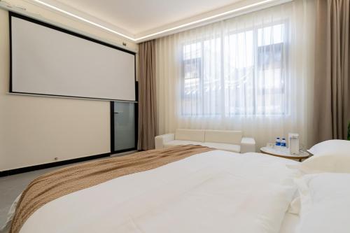 a bedroom with a large white bed and a large screen at Wuyi Whispering Maple in Dali