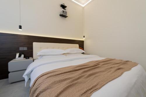 a bedroom with a large bed with white sheets and pillows at Wuyi Whispering Maple in Dali