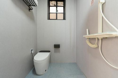 a white bathroom with a toilet and a window at Wuyi Whispering Maple in Dali