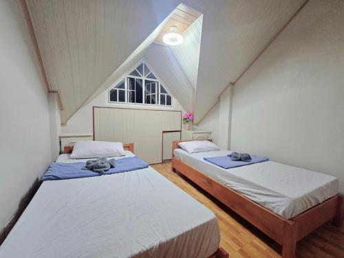 two beds in a room with a large window at 35 Amistad Guesthouse in Baguio