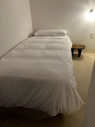 a bedroom with a white bed and a wooden bench at Apartamento de diseño 2 habitaciones in Móra la Nova