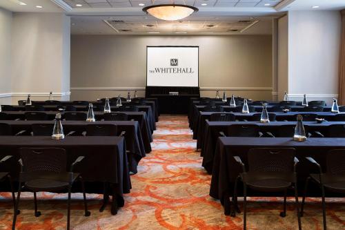 a conference room with tables and chairs and a screen at The Whitehall Houston in Houston