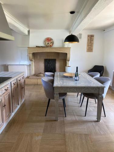 une cuisine avec une table et des chaises ainsi qu'une cheminée dans l'établissement Le Refuge de Bourgogne, à Poisson