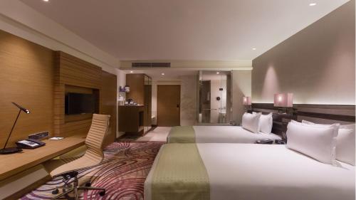 a hotel room with two beds and a desk at Holiday Inn Jaipur City Centre by IHG in Jaipur