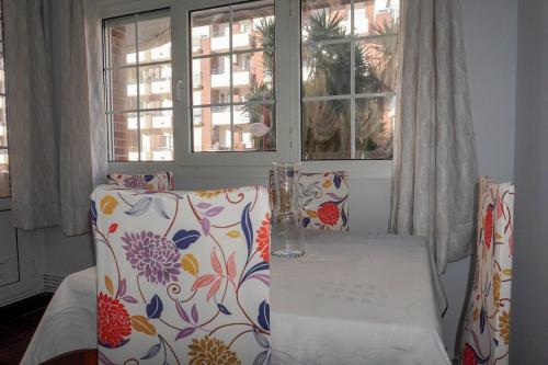 a table and two chairs in a room with a table and windows at Apartamento con piscina de junio a septiembre y a 100 m de la playa in Castro-Urdiales