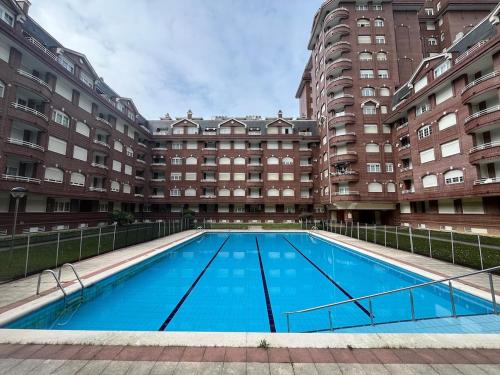 a large swimming pool in front of a building at Apartamento con piscina de junio a septiembre y a 100 m de la playa in Castro-Urdiales