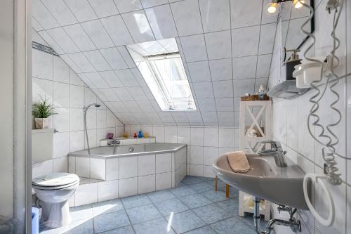 a bathroom with a toilet and a sink and a tub at Wohnung Hallighof in Honkenswarft