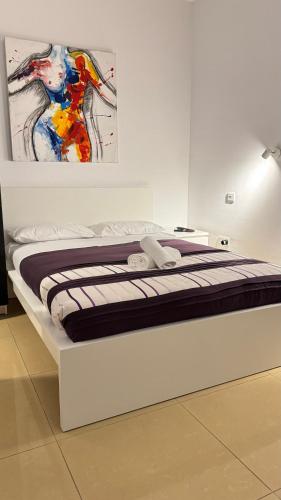 a bed in a room with a painting on the wall at FP Spinola Whole Apartment - FREE WI-FI in St Julian's