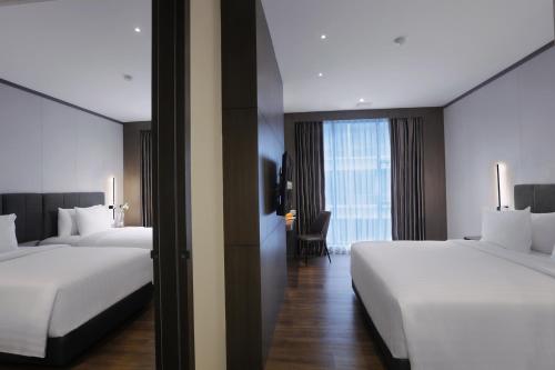 a hotel room with two beds and a window at Harper Premier Nagoya Batam in Nagoya