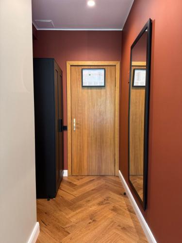 a hallway with a wooden door and a mirror at Avitar in Rīga
