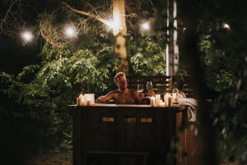 a man sitting in a hot tub at night at Glamp Podróżnika i Marzyciela in Rogówko