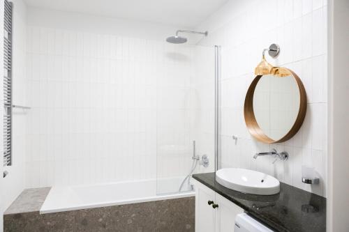 a white bathroom with a sink and a mirror at Browar Hevelius Apartments by Grand Apartments in Gdańsk