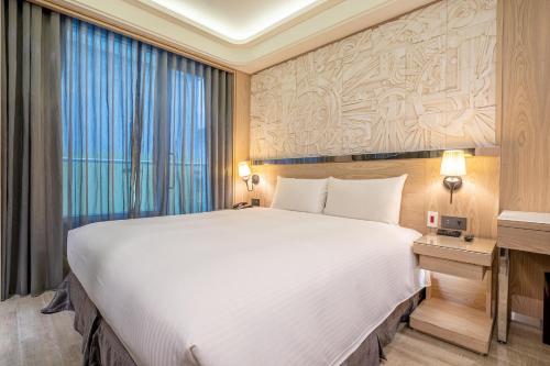 a bedroom with a large bed and a large window at Guide Hotel Taichung Ziyou in Taichung