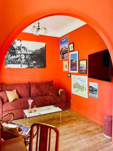 an orange living room with a couch and a table at La Maison au toit vert in Espalion