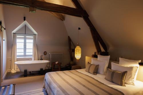 a bedroom with a large bed and a bath tub at Domaine de Locguénolé & Spa - Relais & Chateaux in Kervignac