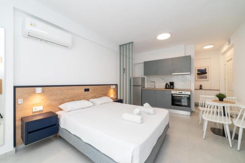 a bedroom with a large white bed and a kitchen at Antigone Residential Complex in Ofrínion