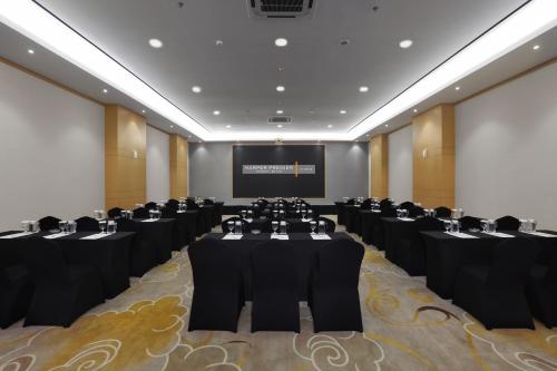 a conference room with black tables and chairs and a screen at Harper Premier Nagoya Batam in Nagoya