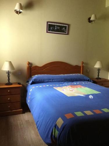 a bedroom with a bed with a blue comforter at Casa Rural Bermeja in Soto de Valdeón