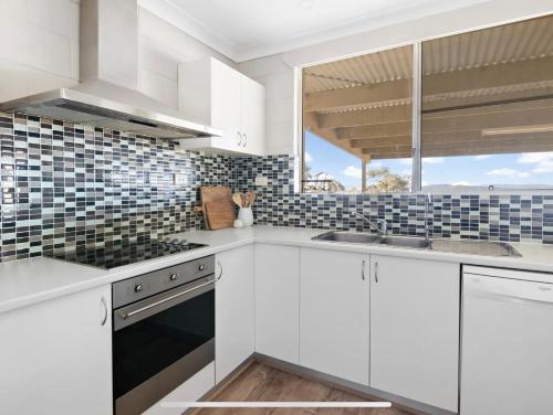eine Küche mit weißen Schränken und einer Spüle und einem Fenster in der Unterkunft Cosy Farm stay minutes from heart of Mudgee in Wilbertree Flat