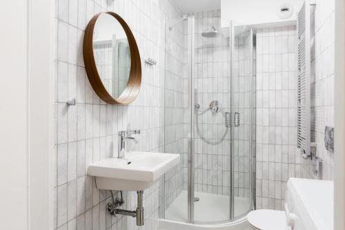a white bathroom with a sink and a shower at Browar Hevelius Apartments by Grand Apartments in Gdańsk