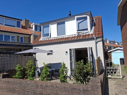 a white house with a fence and an umbrella at T-Rots, prachtig zomerhuis in Noordwijk aan Zee
