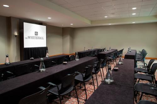 a conference room with tables and chairs and a screen at The Whitehall Houston in Houston
