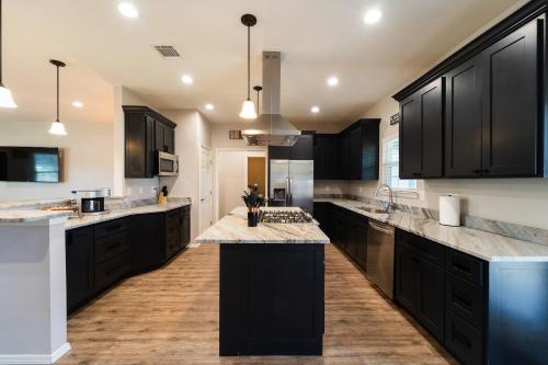 a large kitchen with black cabinets and marble counter tops at Lone Star Getaway I Rec Barn I Fire Pit Nights I Movie Night Projector in Fischer
