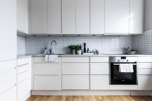 a white kitchen with white cabinets and appliances at Biz Apartment Gärdet in Stockholm