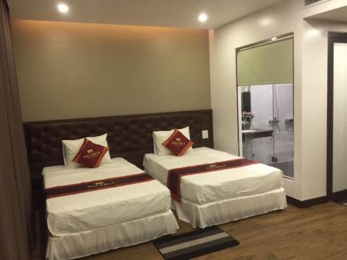 two beds in a room with a mirror at Melanta Hotel - FLC Sầm Sơn in Sầm Sơn