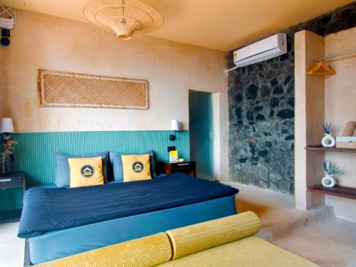 a bedroom with a blue bed and a stone wall at The Hosteller Bhandardara in Bhandardara 