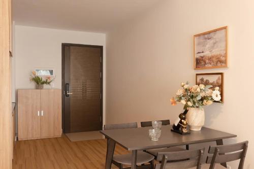 a dining room with a table and a vase with flowers at Otis Soho Saigon Balcony Apartment in Ho Chi Minh City