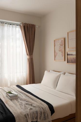 a bedroom with a white bed and a window at Otis Soho Saigon Balcony Apartment in Ho Chi Minh City