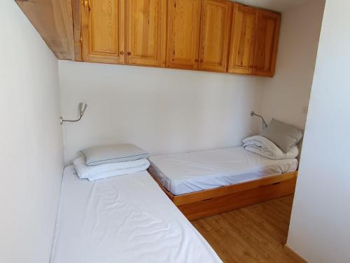 - 2 lits dans une petite chambre avec des armoires en bois dans l'établissement Appartement 2 chambres, 4 pers, terrasse, animaux acceptés, proche pistes et commerces - Montgenèvre - FR-1-445-80, à Montgenèvre