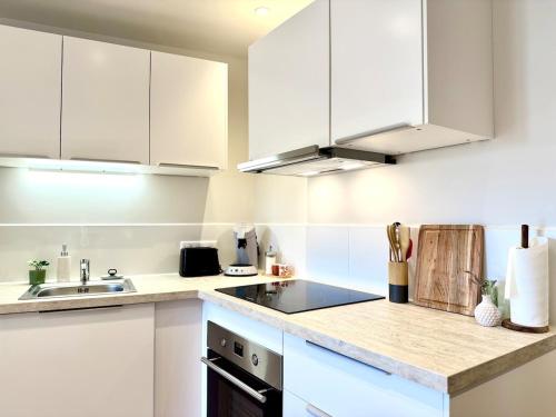 a kitchen with white cabinets and a sink at Le Cosy Bruey - Appartement Confort au Cœur du Centre Historique - Balcon & Patio in Orange