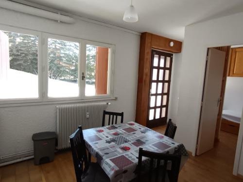 une salle à manger avec une table et deux fenêtres dans l'établissement Appartement 2 chambres, 4 pers, terrasse, animaux acceptés, proche pistes et commerces - Montgenèvre - FR-1-445-80, à Montgenèvre