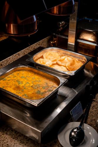 two trays of food in pans on a stove at Serene Resort Hyderabad in Shamshabad