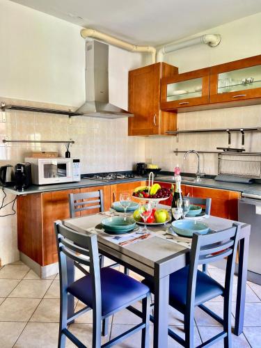 a kitchen with a table with blue chairs and a sink at house prua a step from the lake in Bellano