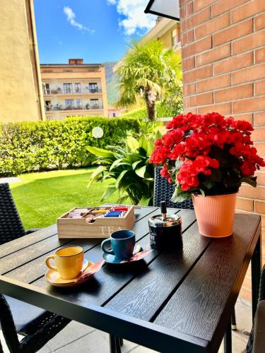 a wooden table with cups and a vase of red flowers at house prua a step from the lake in Bellano