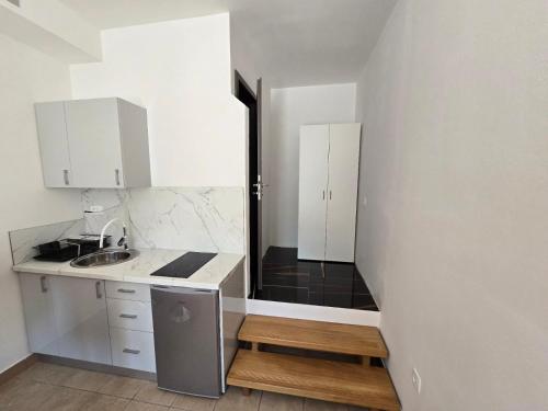 eine kleine Küche mit weißen Schränken und einer Spüle in der Unterkunft Apartments Knežević in Jadranovo