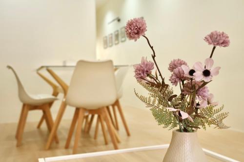 a vase with flowers in it next to a table and chairs at Ilik House ไอลิกเฮ้าส์ in Hat Yai