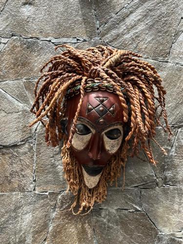 a mask is hanging on a stone wall at Boutique Hotel Luz da Lua in Ponta do Sol
