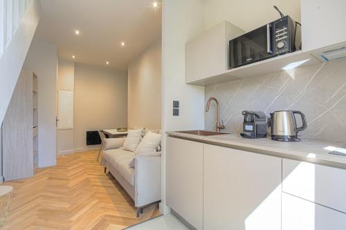 une cuisine et un salon avec un canapé dans l'établissement Appartement contemporain au calme, Ecully, à Écully
